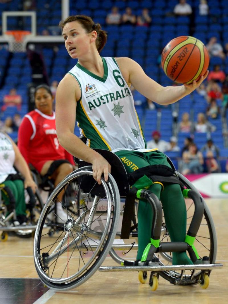 A female wheelchair basketball player is dribbling the ball during a game